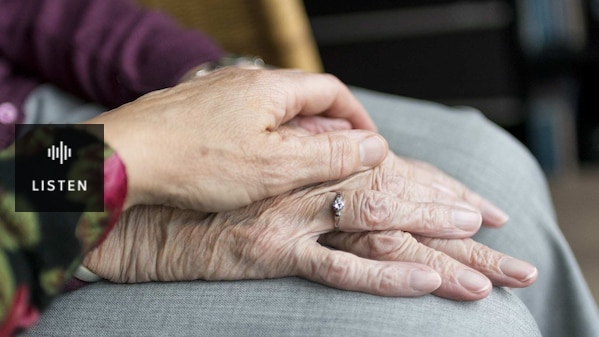 A close-up shot of a hand resting on an elderly woman's hands. Has Audio.
