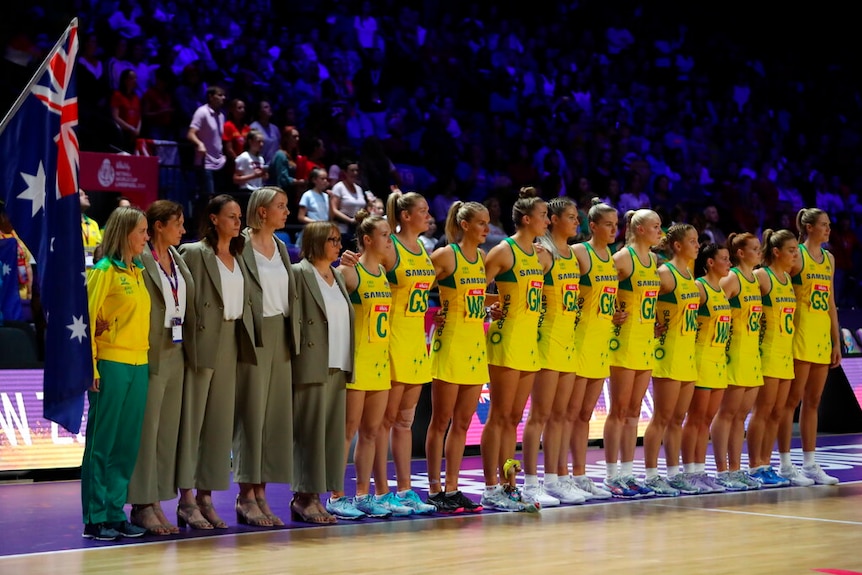 A team of female netballers stand in a line during the pre-game anthem