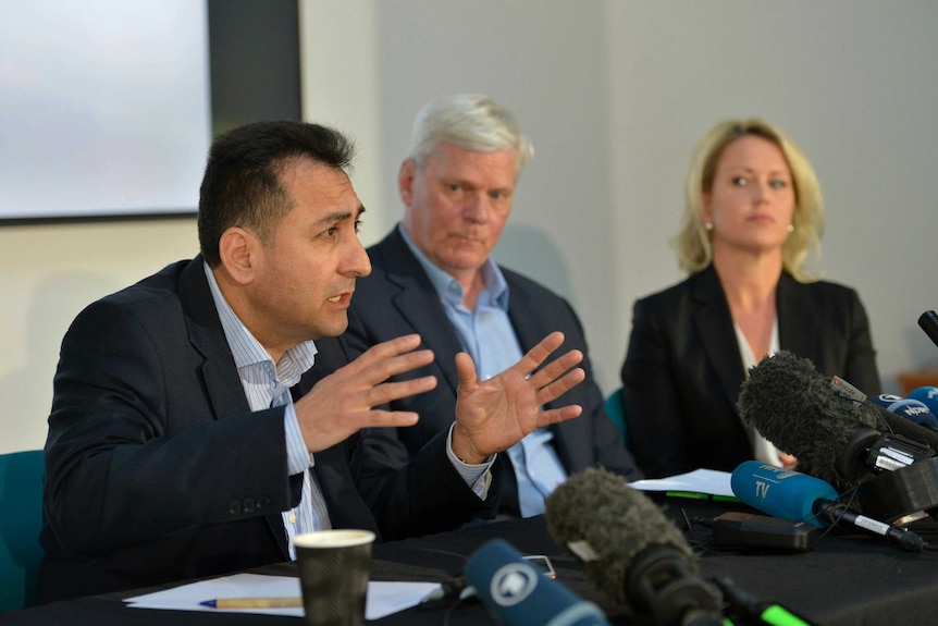 Fidel Narvaez speaking into a microphone gesturing with his hands as Kristinn Hrafnsson and Jennifer Robinson look on.