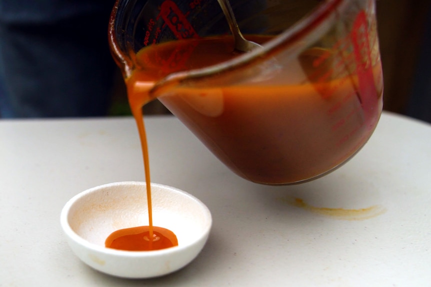 Chilli oil is poured from a jug into a small dish.