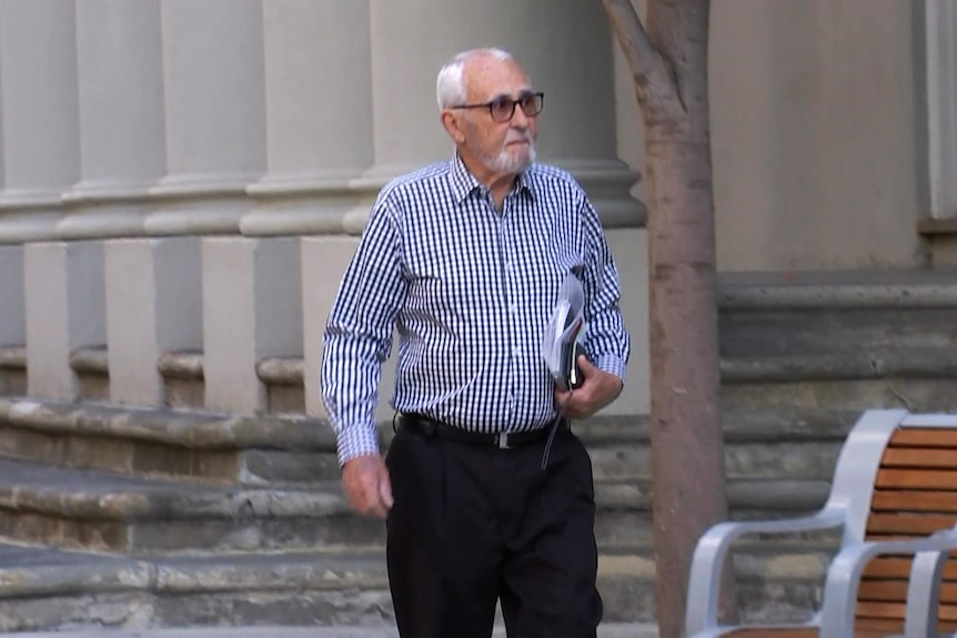 Jay Walsh wears formal attire and glasses as he walks into court