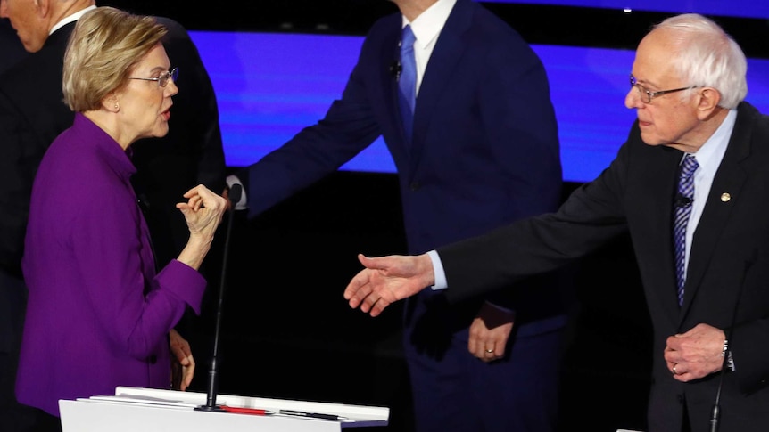 A woman in a purple blazer does not return the outstretched hand of a man in a suit