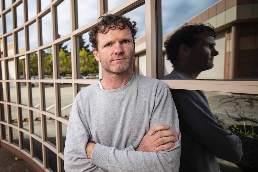 Man standing in front of windows looking at the camera