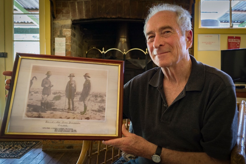 Man holds old photo of the men from the 1st Light Horse Brigade