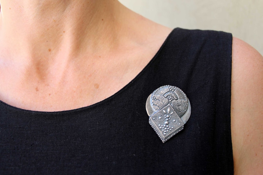 A close-up of a women's neck and an ornate broach.