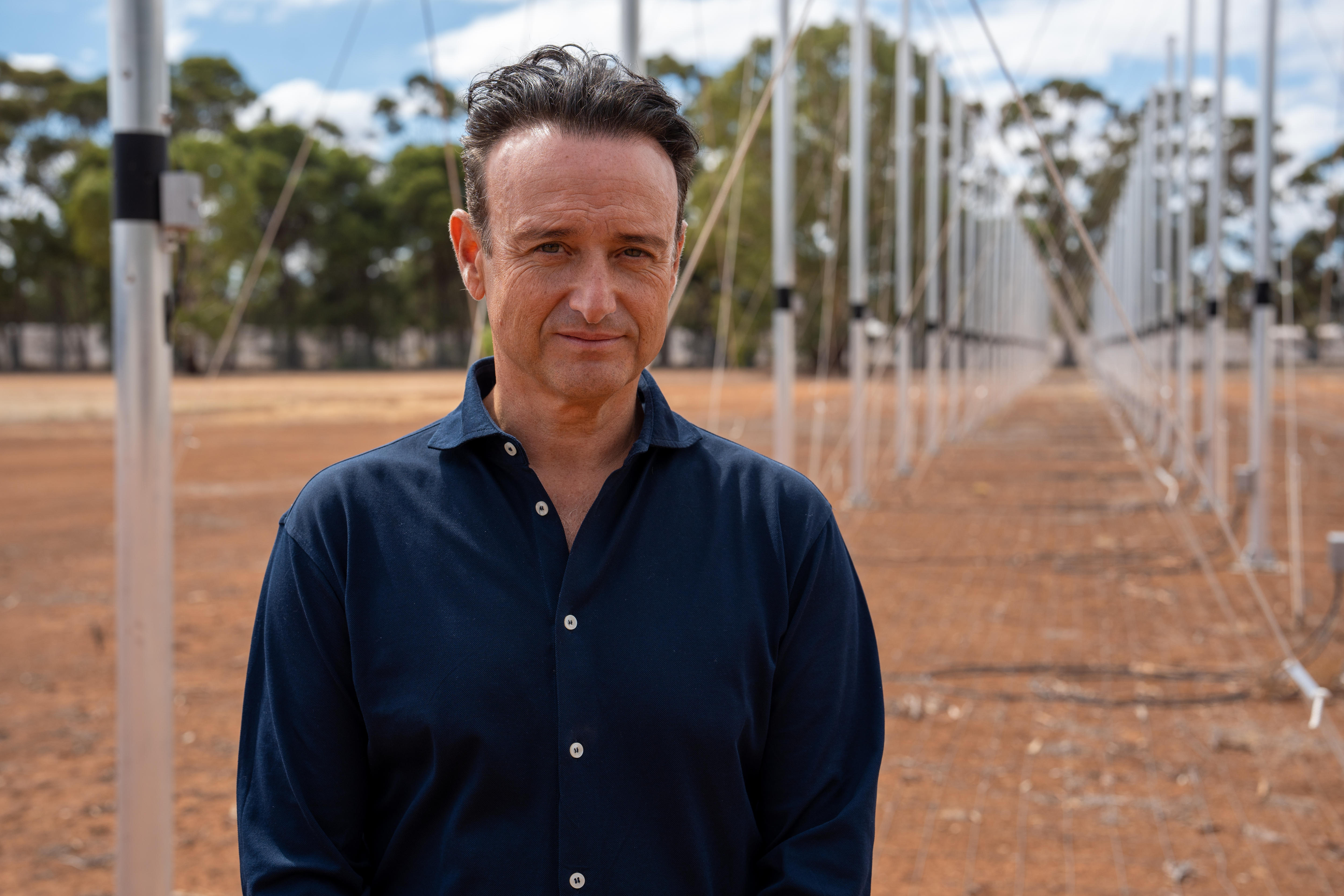 A man stands in front of rows and rows of antennas.