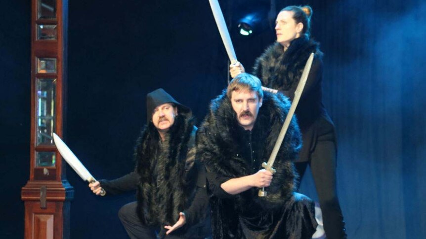 Performers from UK trio Graeme of Thrones on stage wielding swords as part of their act.
