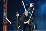 Performers from UK trio Graeme of Thrones on stage wielding swords as part of their act.