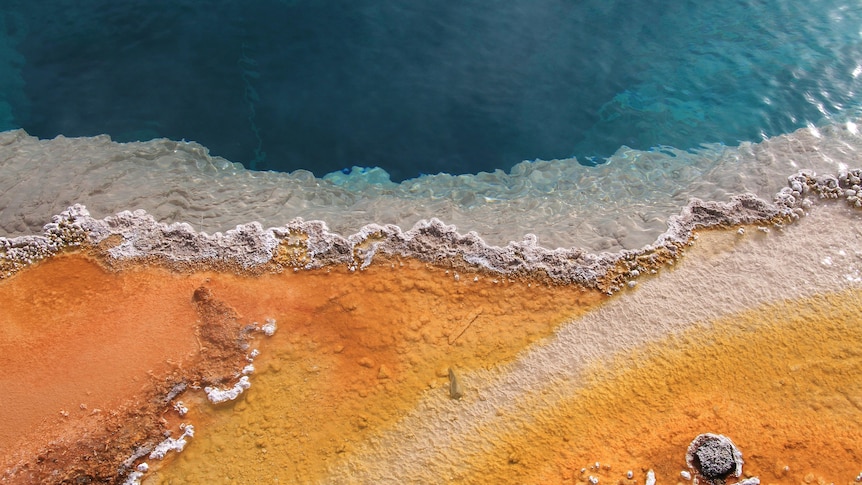 An aerial view of a hot spring with deep water and foam