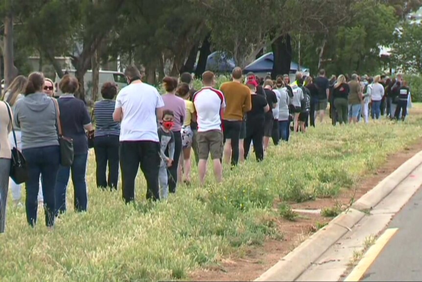 A queue of hundreds of people stand in line at a pop-up testing clinic