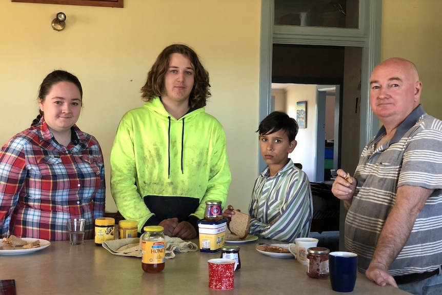Father and three children stand around breakfast table