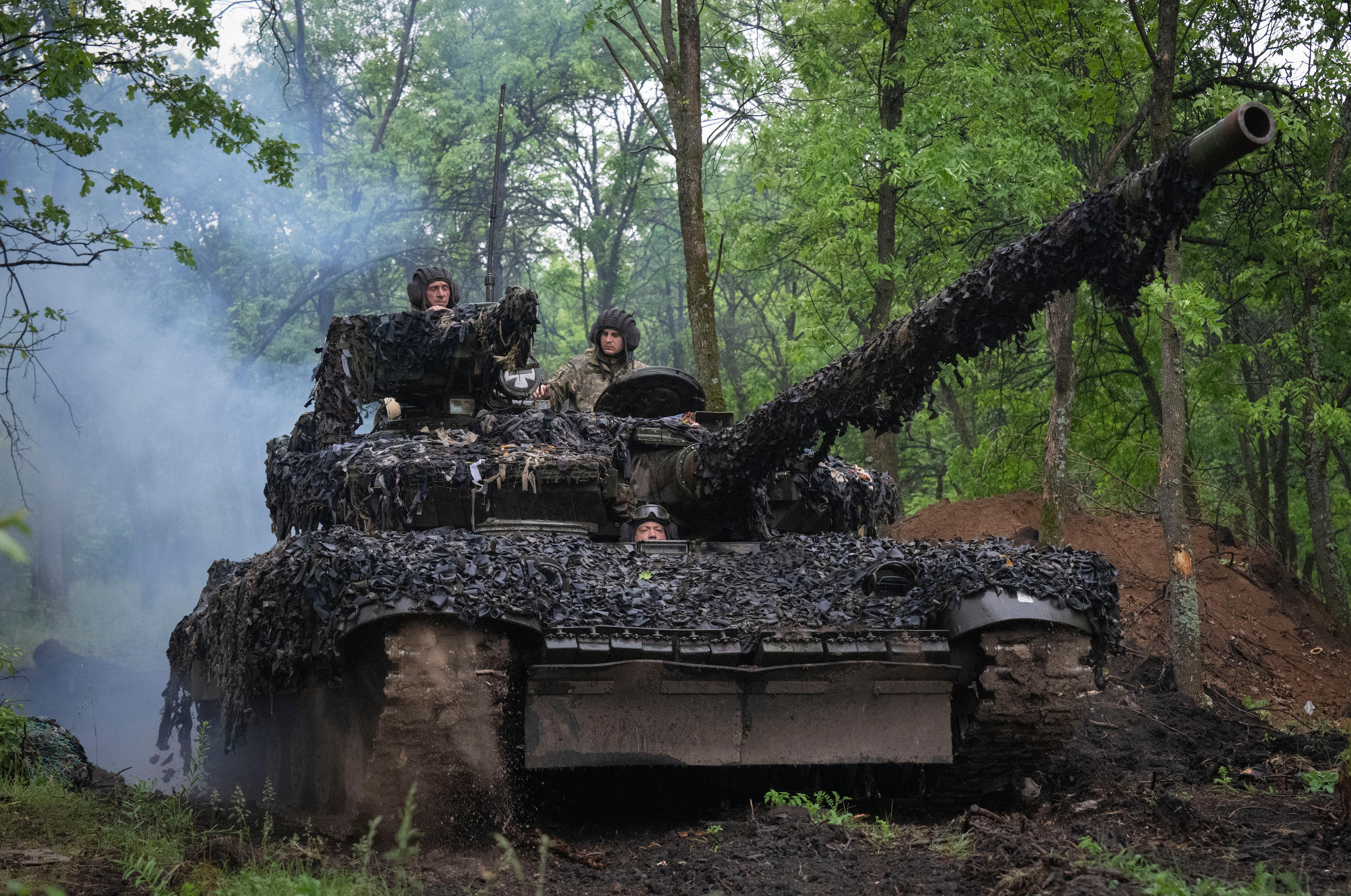 Three men seen in a tank in the woods.