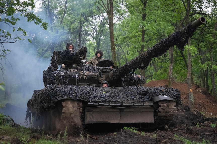 Three men seen in a tank in the woods.