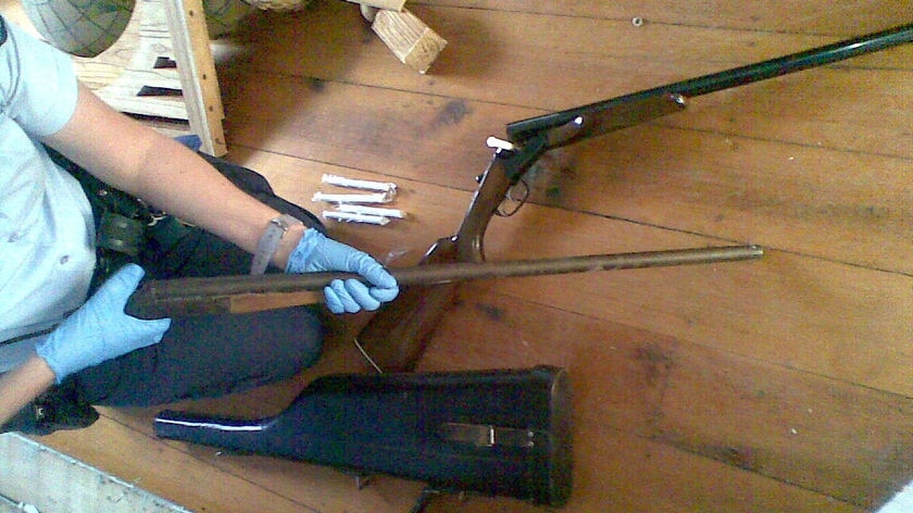 A Queensland police officer examines shotguns