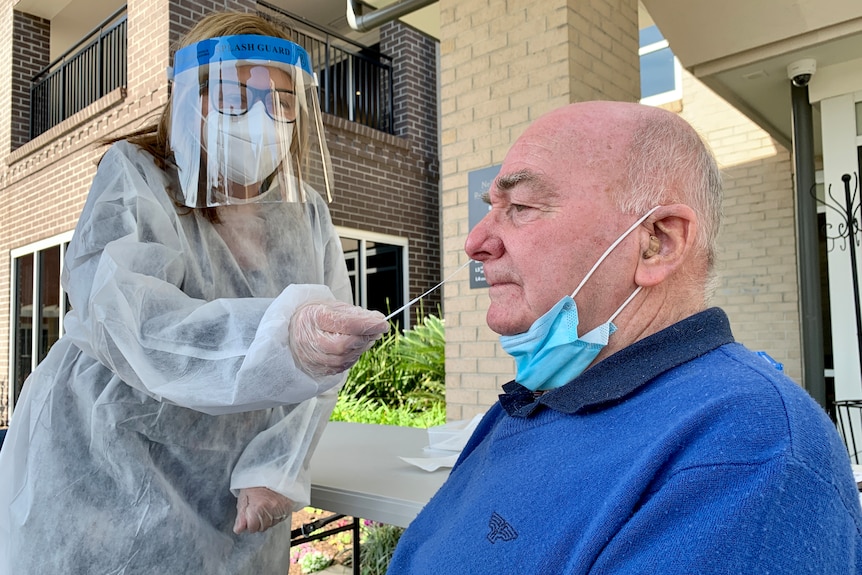 A man getting a COVID-19 test from a nurse wearing a face shield.