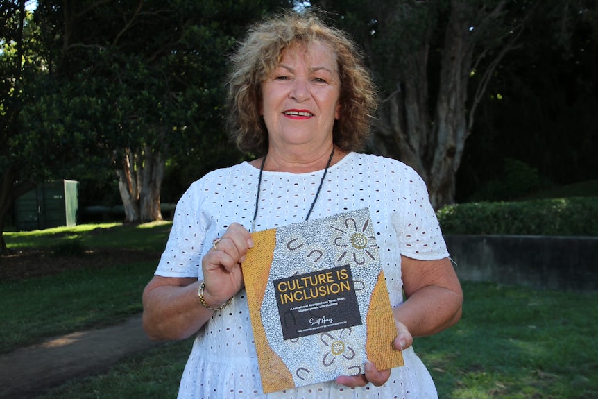 a woman holding a book standing outdoors