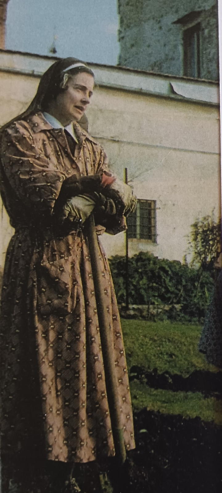 Uma foto antiga de uma mulher com um hábito marrom de freira.