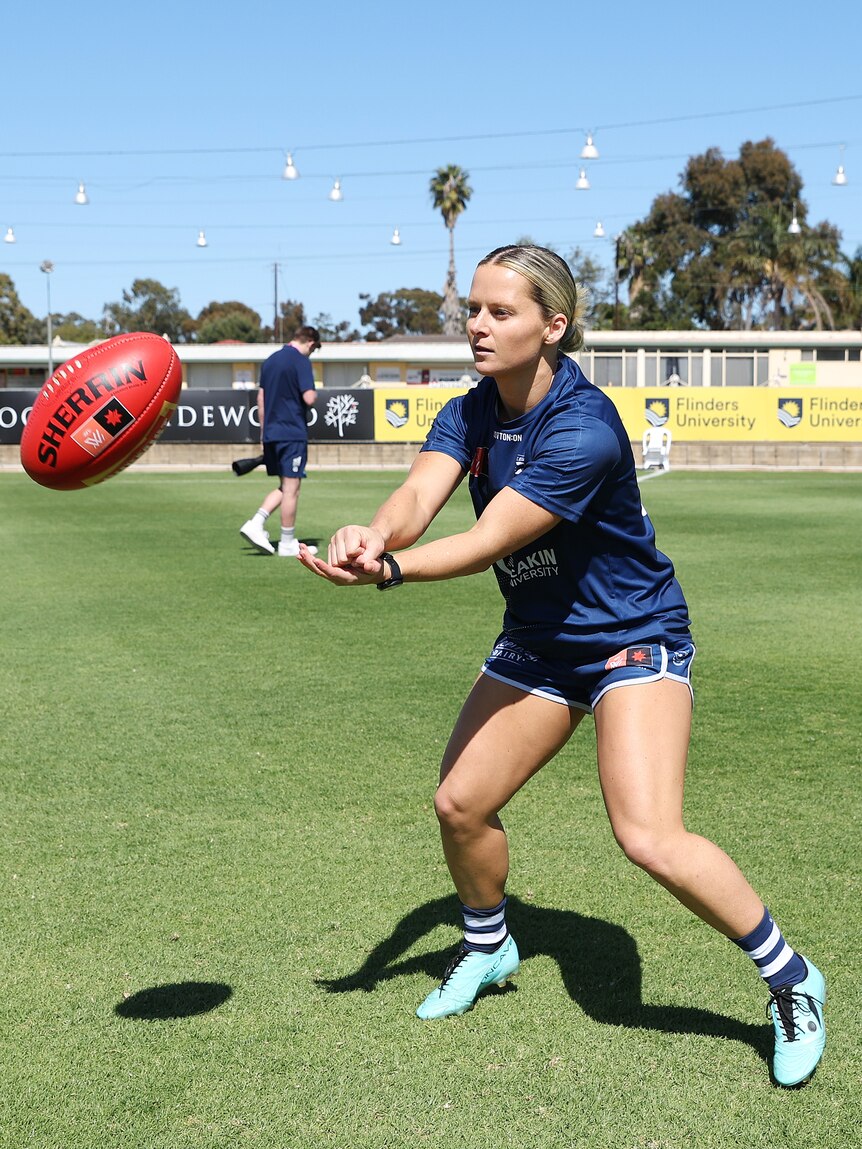 Kate Surman handballs the ball at Geelong training at Alberton Oval