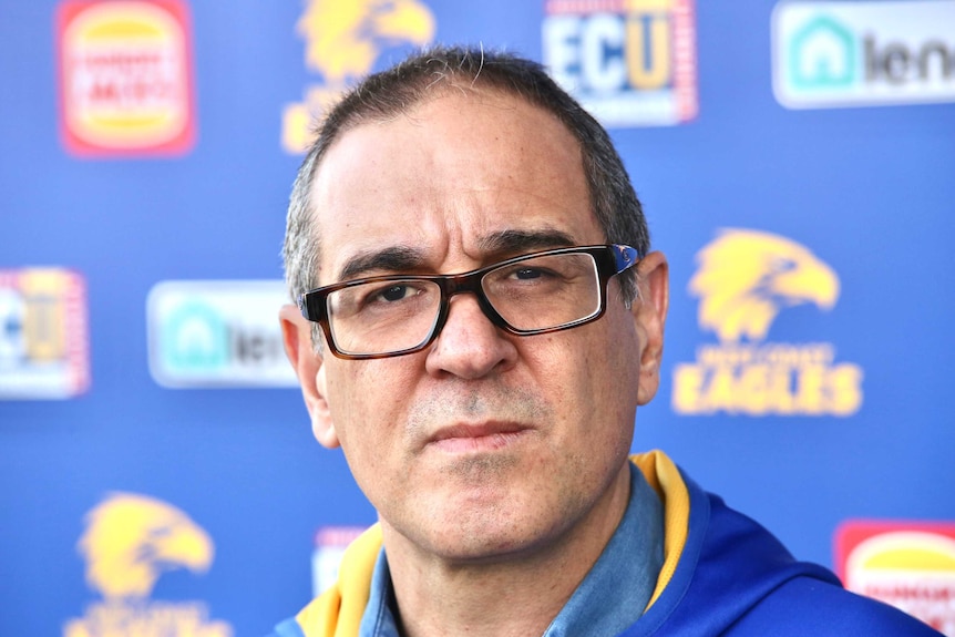 Craig Vozzo, wearing glasses and an Eagles hoody stares into the camera in front of a blue wall.