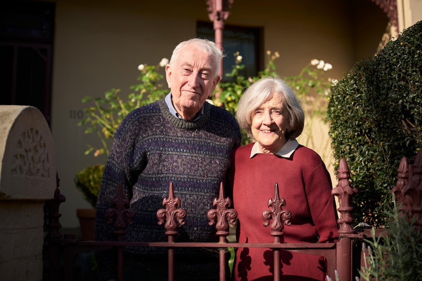 Peter and Penny stand in front of their home, smiling.