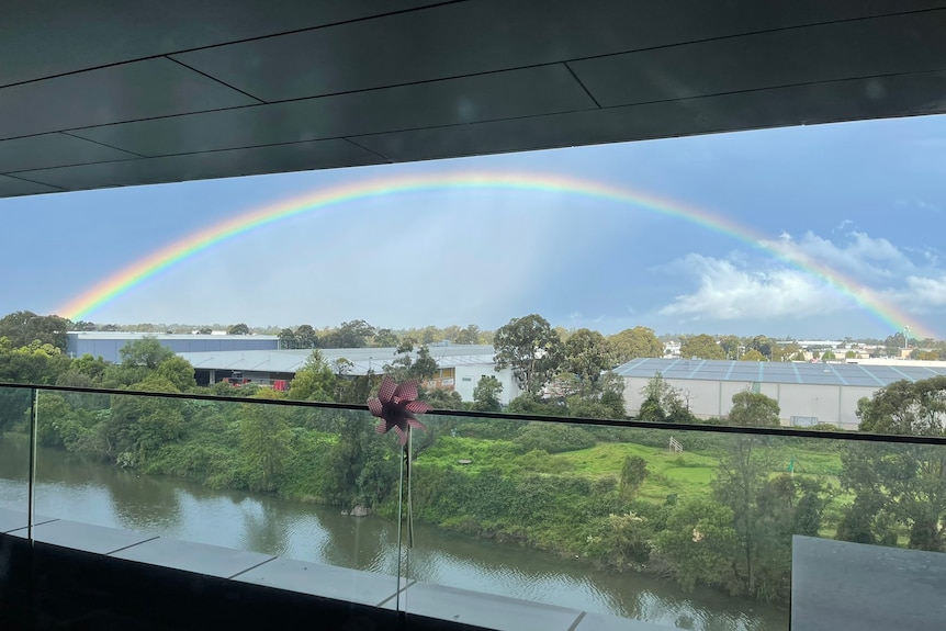 A full rainbow viewed from a balcony in Sydney after a storm