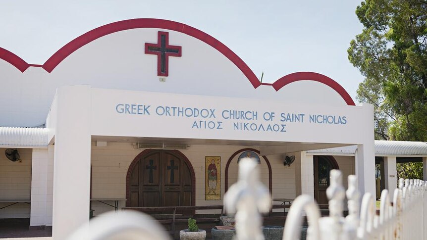 A photo of a white Greek church with maroon detailing.