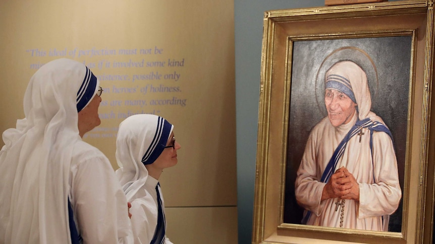 Sisters of the Missionaries of Charity look at the official canonisation portrait of Mother Teresa