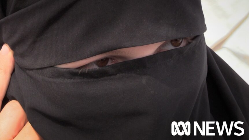 A close up of a woman's eyes which are visible through an opening in her hijab