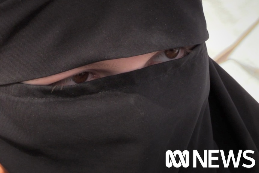 A close up of a woman's eyes which are visible through an opening in her hijab