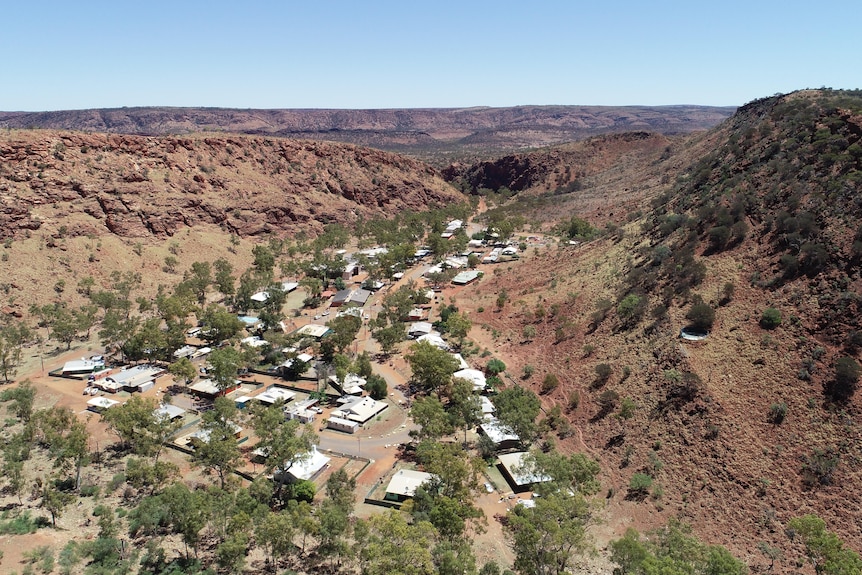 Aerial shot of white houses in a valley, with some green bush nearby.