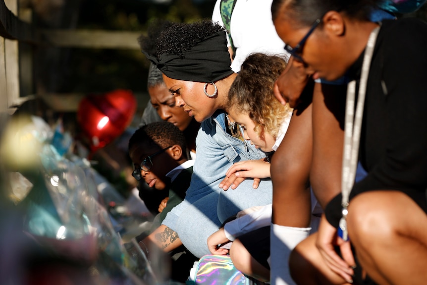 A group of women and children look at floral tributes for murdered teacher Sabina Nessa 