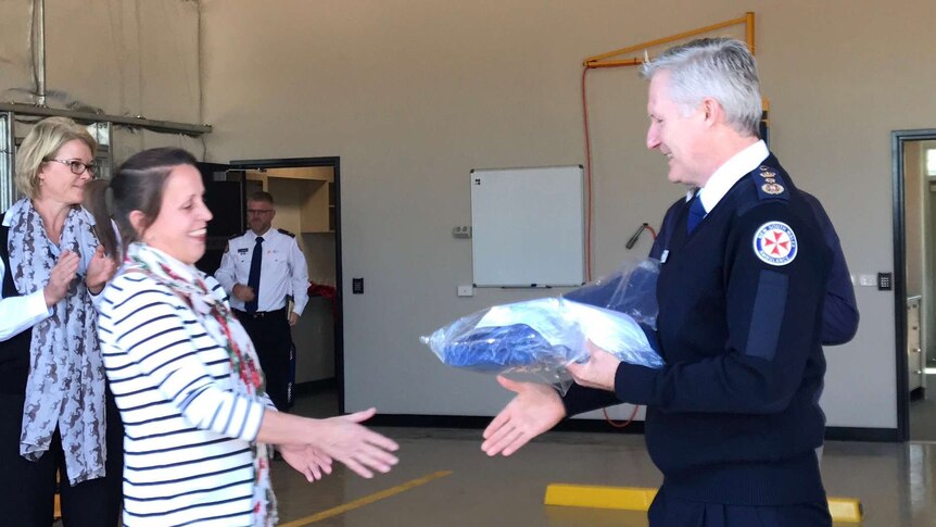 Volunteer shakes hands with head of NSW ambulance receiving her uniform at Coolamon station