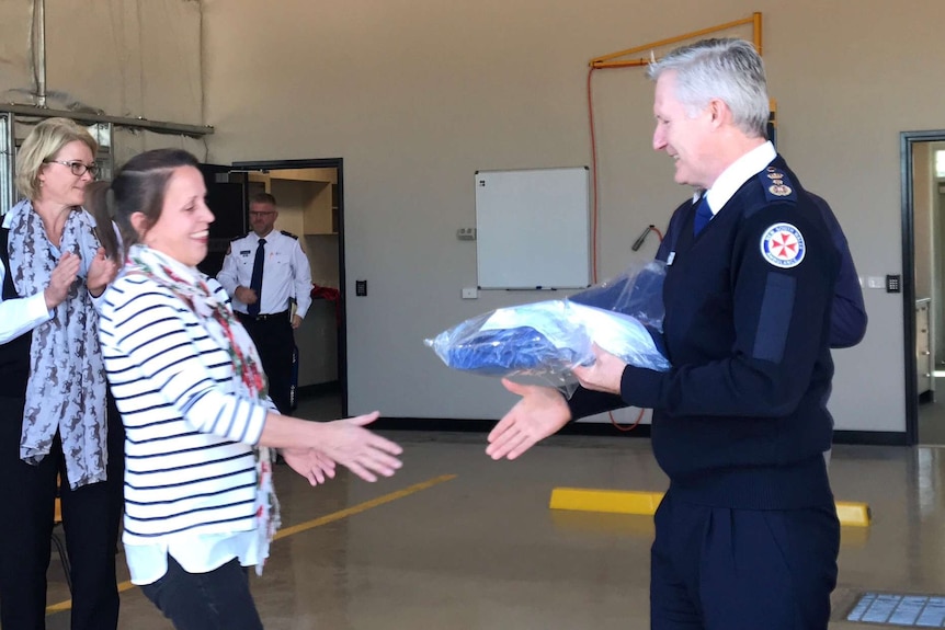 Volunteer shakes hands with head of NSW ambulance receiving her uniform at Coolamon station