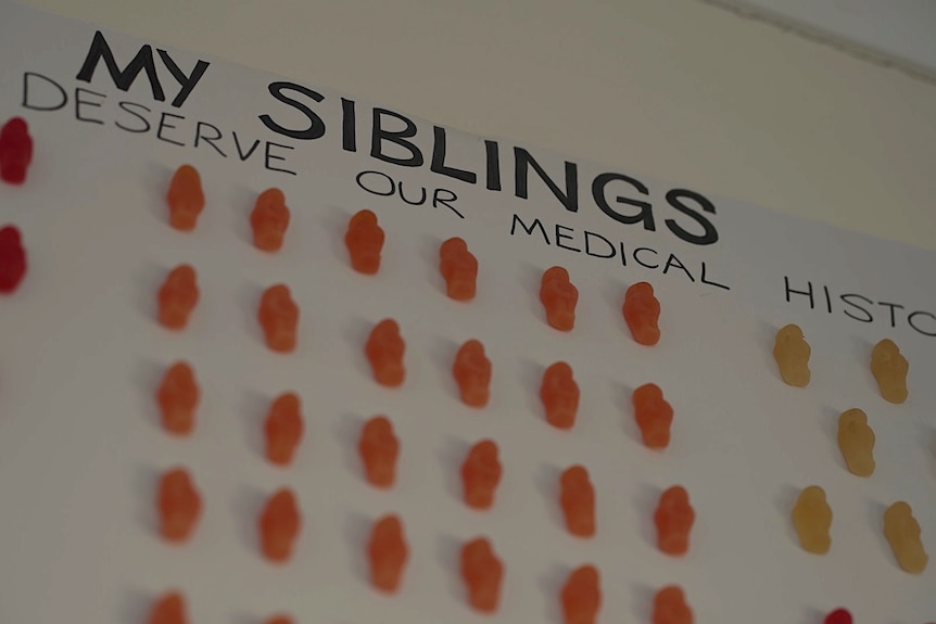 A close-up of a sign saying 'My siblings' with multiple jelly babies stuck to it