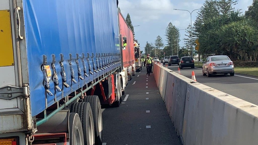 A police officer walking beside row of stopped trucks.