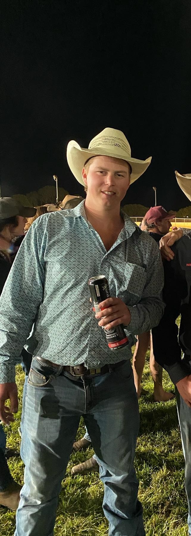 A man wearing a cowboy hat holding a beer