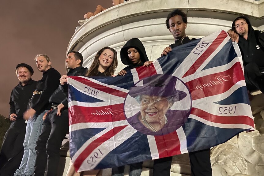 A group of teens hold up a Union Jack bearing the Queen's face 