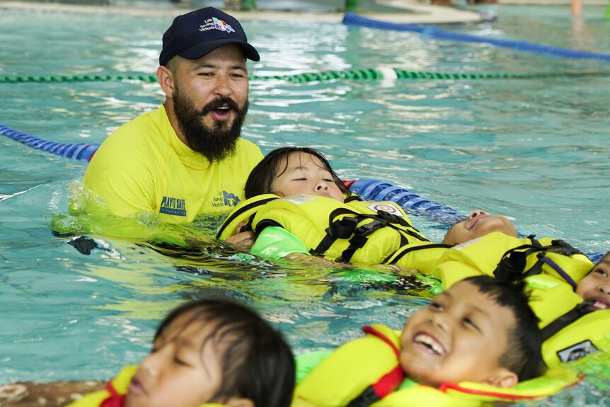 A swimming instructor teaching children to float 