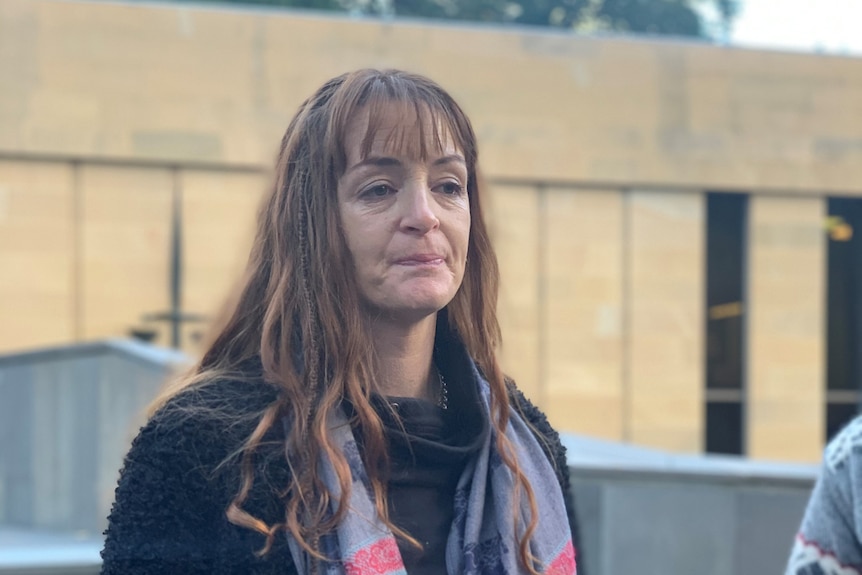 Woman in scarf and woollen coat stands outside Supreme Court 