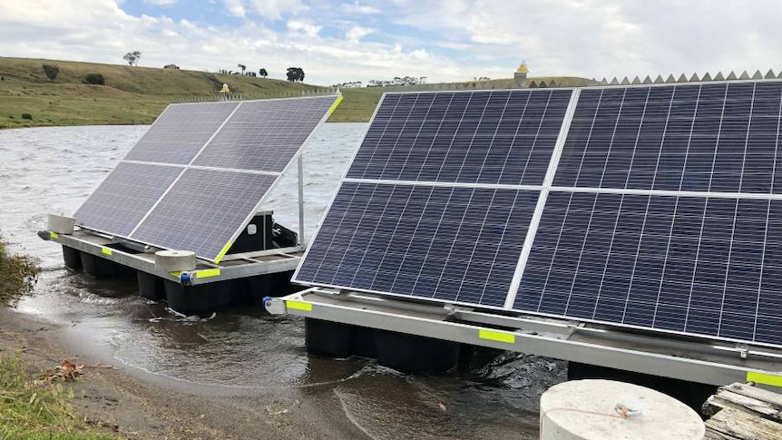 Two solar panels on pontoons in shallow water of a lake