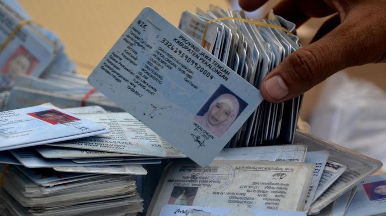 A stack of Indonesian ID cards tied together and scattered.