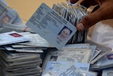 A stack of Indonesian ID cards tied together and scattered.