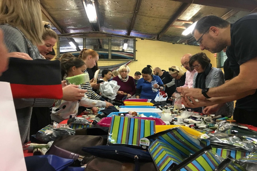 Volunteers sort through donations of toiletries creating charity packs for homeless people.