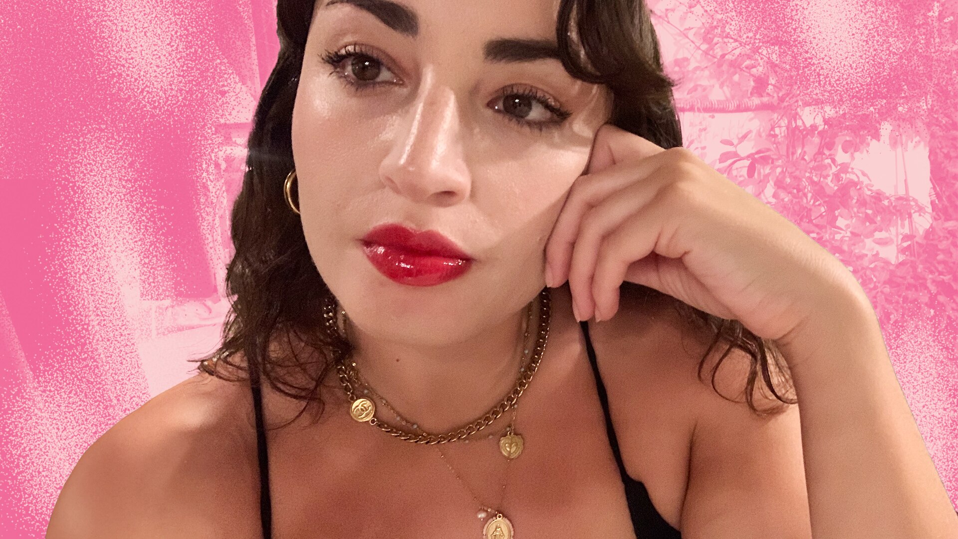 A woman with dark brown hair and red lipstick looks moody and contemplative