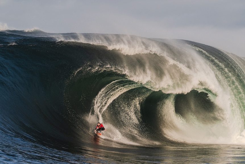 A man surfing a huge wave.
