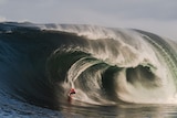 A man surfing a huge wave.