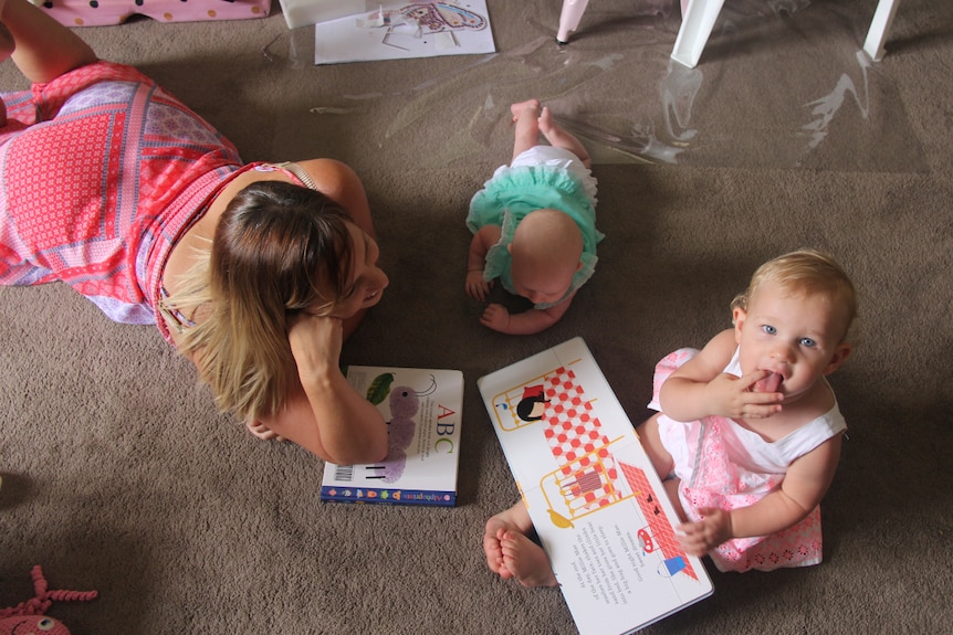 A woman reading books to her two kids