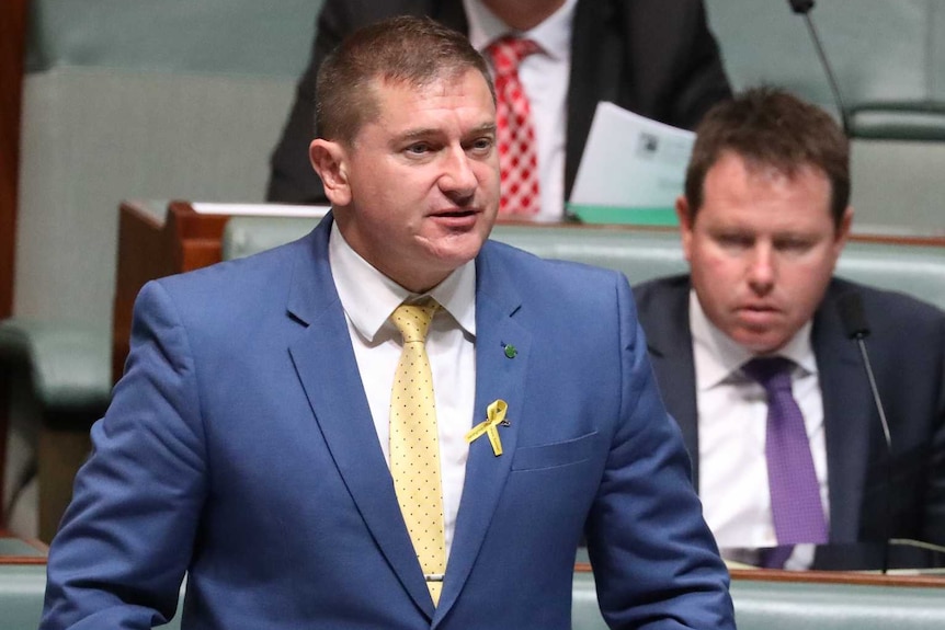O'Brien is wearing a blue suit, standing up, while Barnaby Joyce sits next to him looking up.