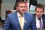 O'Brien is wearing a blue suit, standing up, while Barnaby Joyce sits next to him looking up.