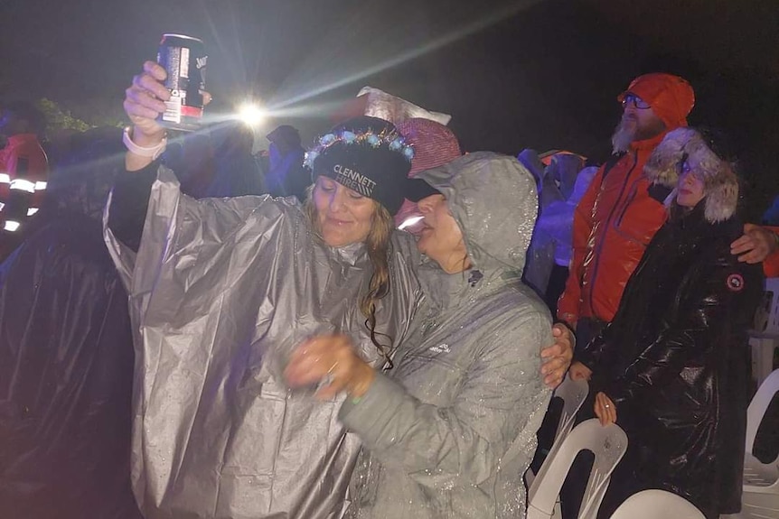Two women in rain gear at a concert.